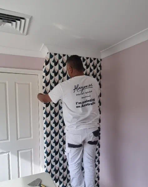 Painter applying wallpaper in a room