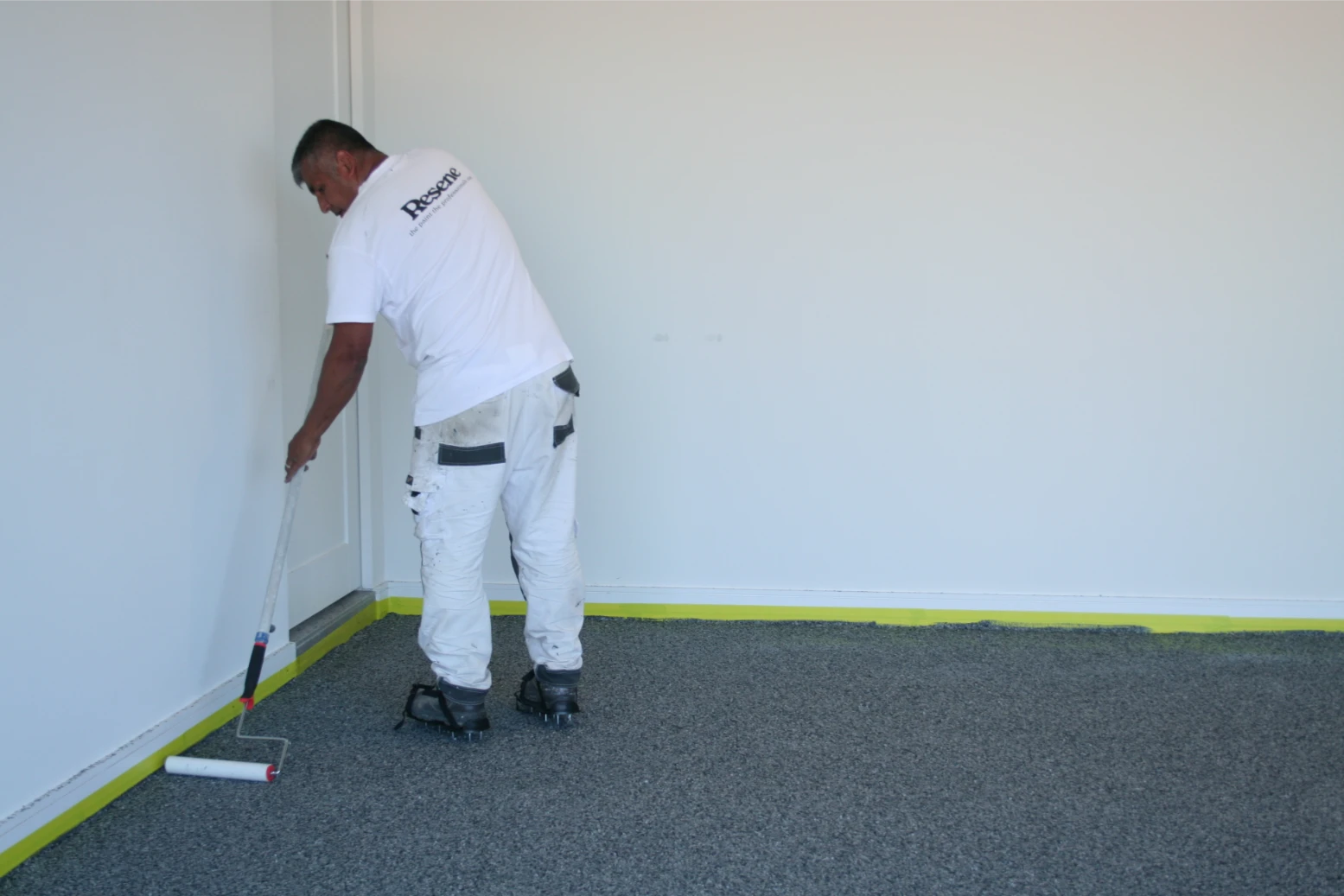 Painter applying white paint on interior wall