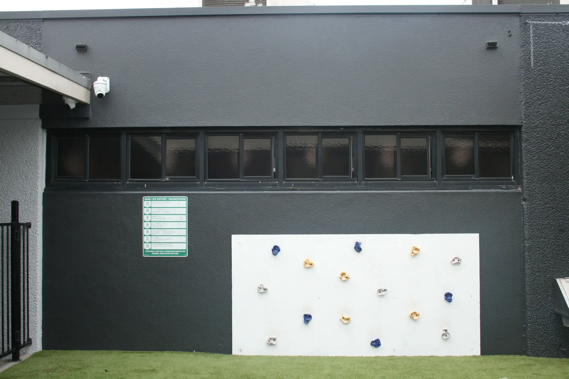 Outdoor climbing wall by dark building with window row