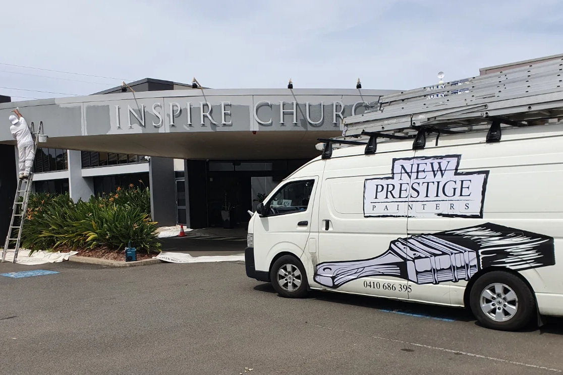 Painter on ladder renovating Inspire Church entrance