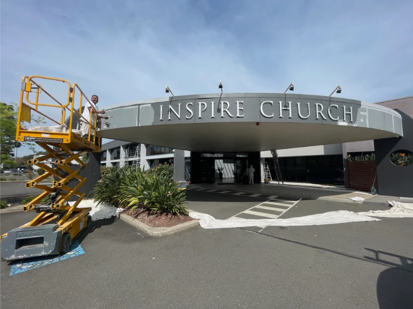 Worker on lift painting Inspire Church entrance
