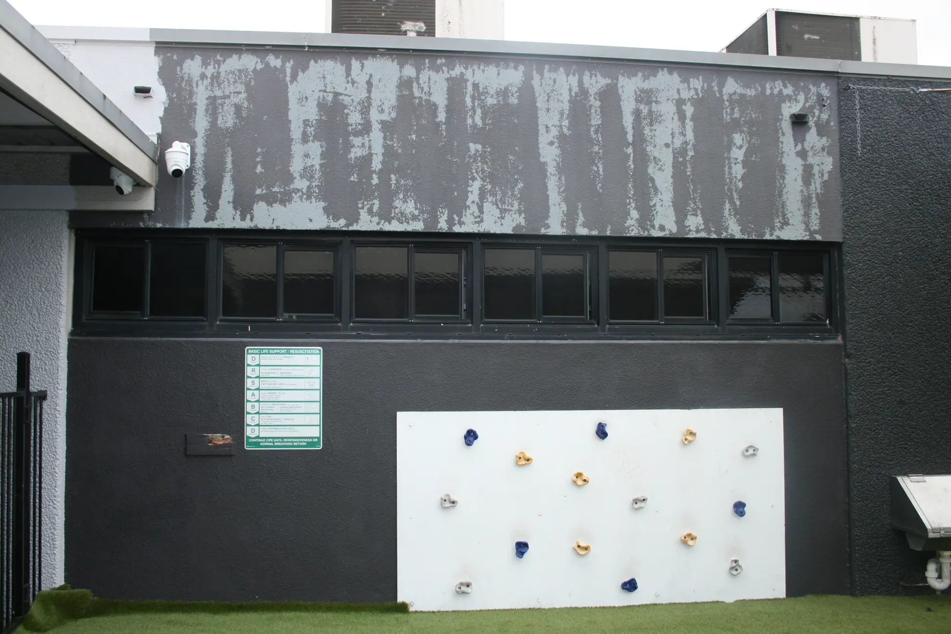 Weathered building with climbing wall and window security bars