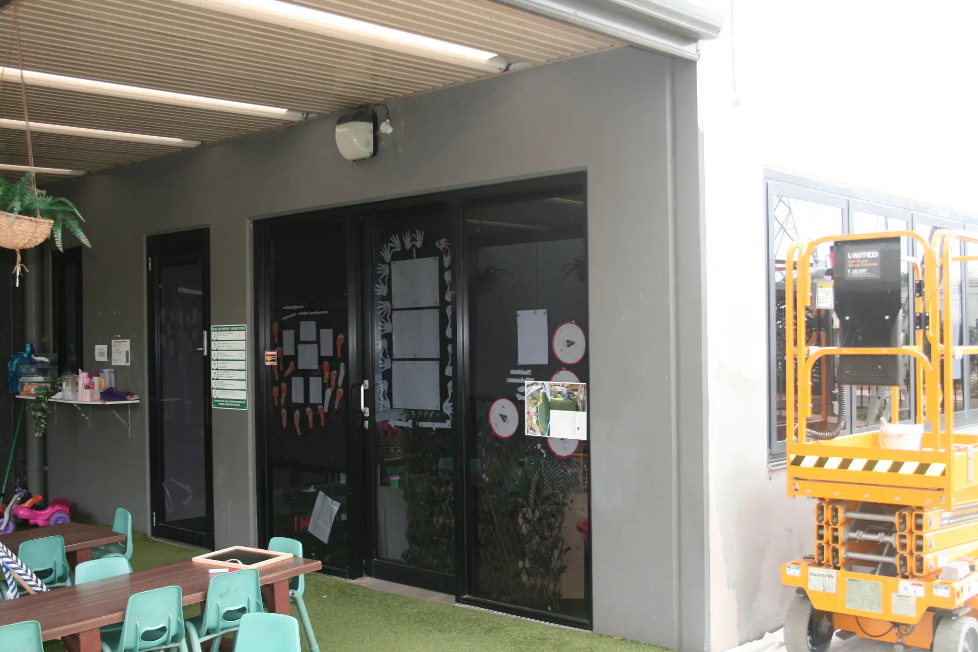 School entrance with chairs, tables, and yellow lift outside
