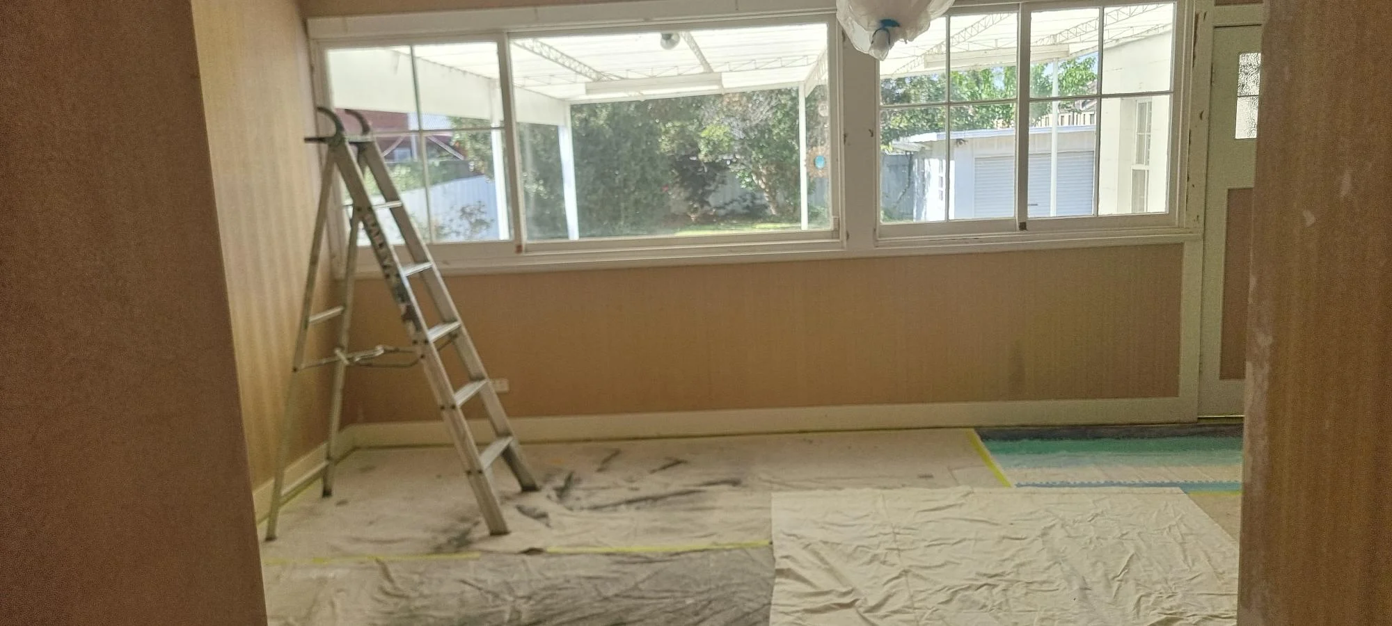 Interior room in renovation with ladder and protective sheets