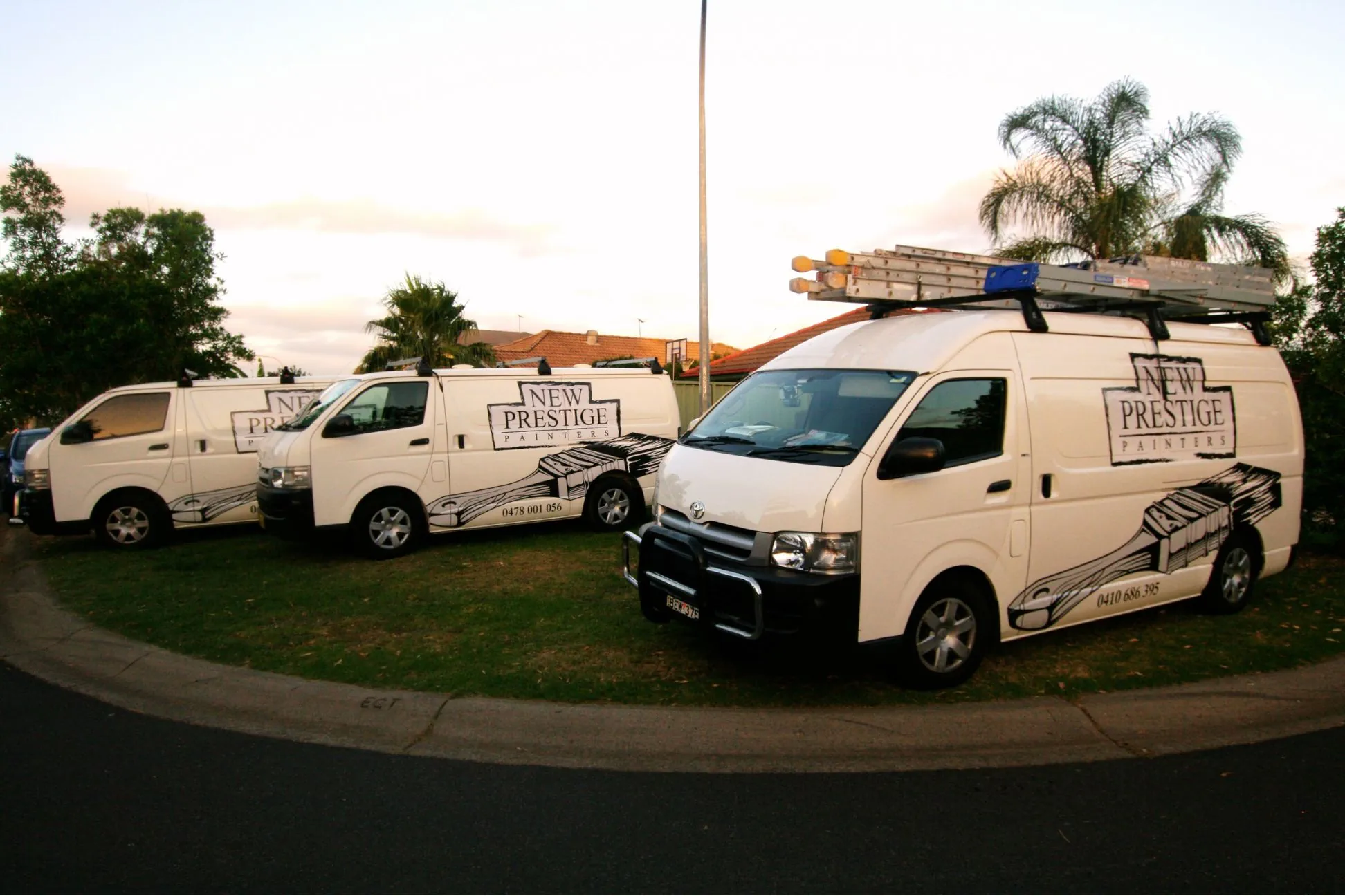 Three branded white vans of New Prestige Painters parked.