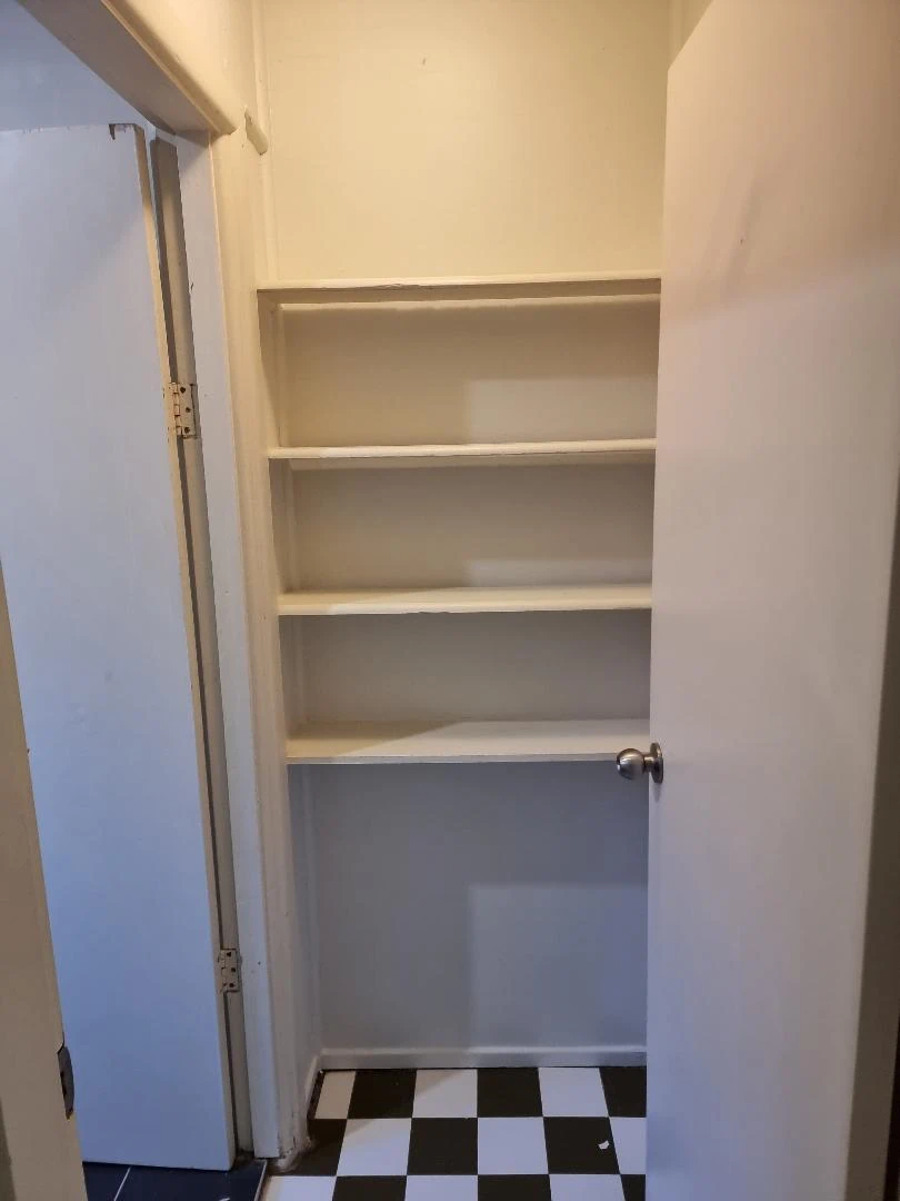 Small room with empty shelves and checkered floor
