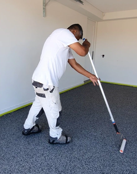 Painter rolling paint on floor in empty room