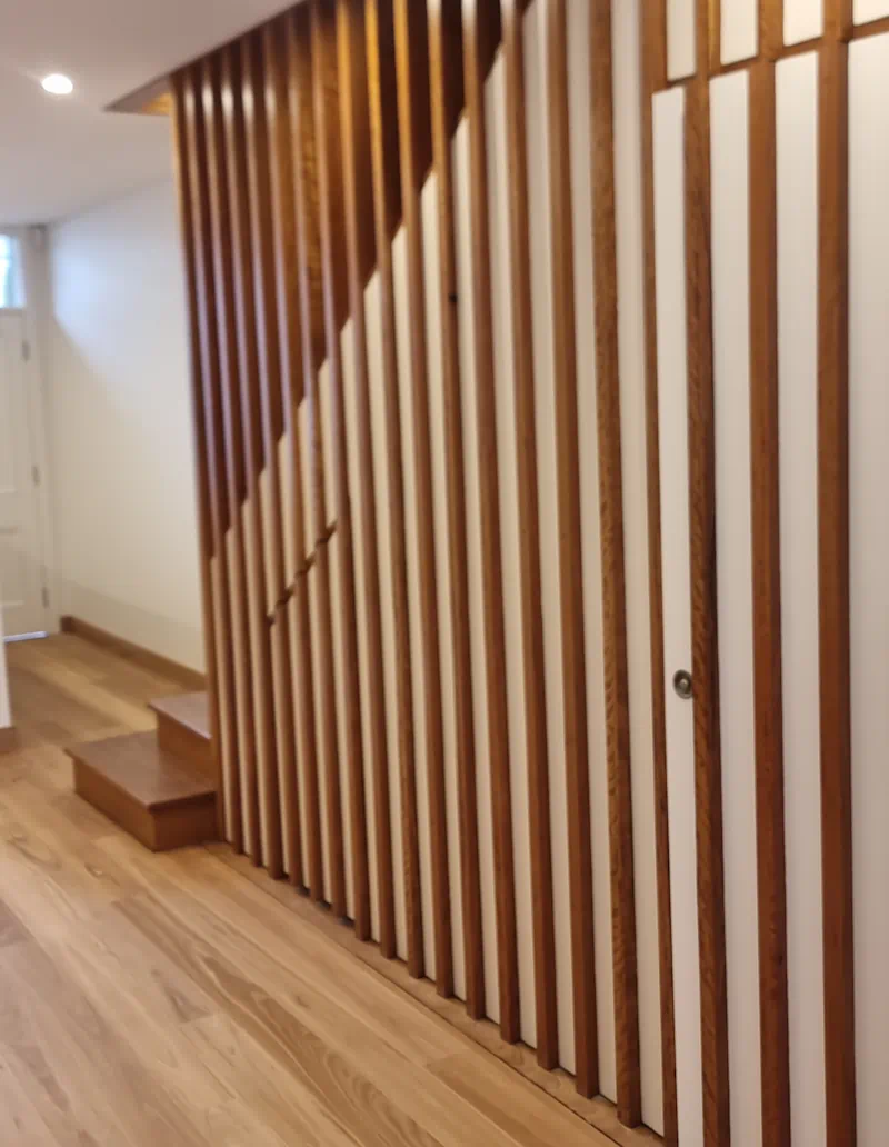 Modern wooden staircase with vertical slats in hallway
